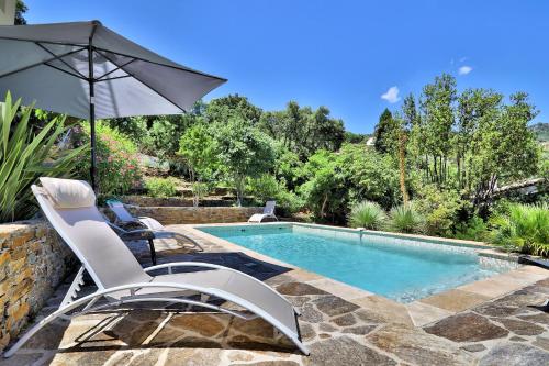 einen Pool mit 2 Stühlen und einem Sonnenschirm in der Unterkunft Lantana luxury property in Bormes-les-Mimosas