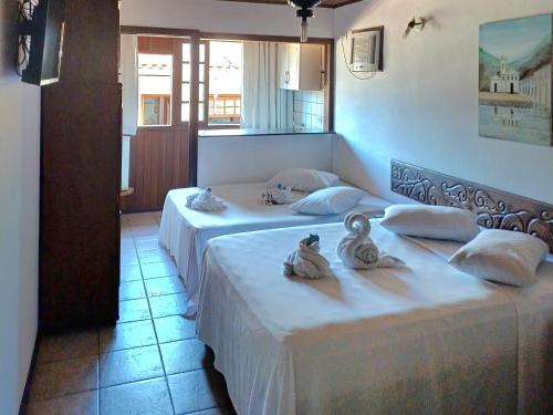 two beds in a hotel room with towels on them at Pousada Village Paraty Centro in Paraty