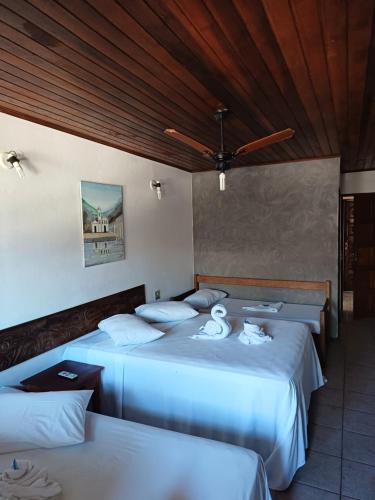 two beds in a hotel room with white sheets at Pousada Village Paraty Centro in Paraty