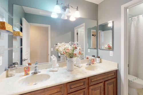 a bathroom with two sinks and a vase of flowers at South Valley Retreat in Avondale