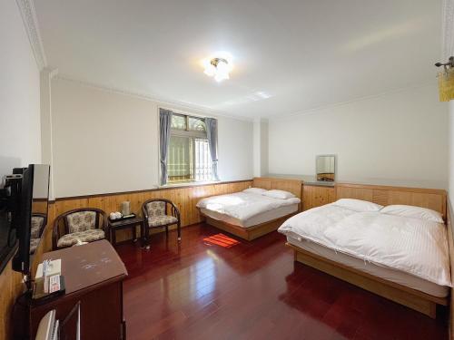 a bedroom with two beds and a table and chairs at Chia Yuen Homestay in Fenqihu