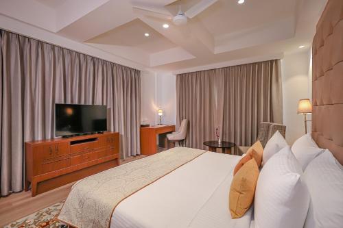 a hotel room with a bed and a flat screen tv at Regenta Dehradun by Royal Orchid Hotels Limited in Dehradun