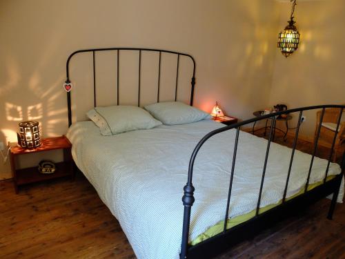 a bedroom with a bed with a black metal frame at La Maison du Voyageur in Les Ilhes