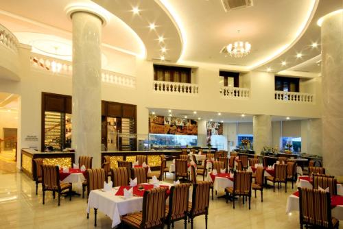 a restaurant with tables and chairs in a building at Nha Trang Palace Hotel in Nha Trang