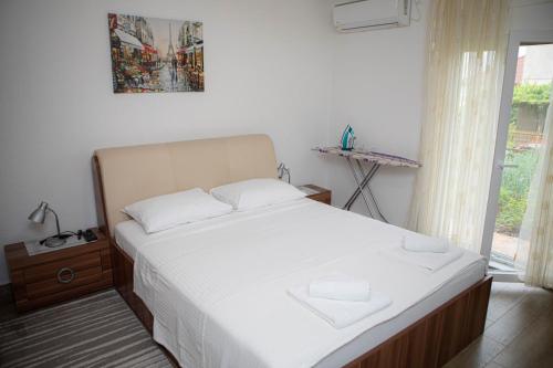 - une chambre avec un lit doté de draps blancs et une fenêtre dans l'établissement Apartmani Budimčić, à Trebinje