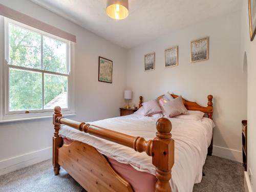 a bedroom with a wooden bed and a window at Diglis Lock Cottage in Worcester