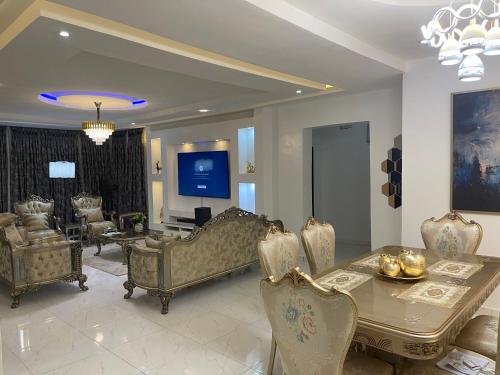 een woonkamer met een tafel en stoelen en een televisie bij Havre Luxury Apartment in Abuja