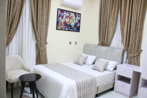 een kleine slaapkamer met een bed en een stoel bij Havre Luxury Apartment in Abuja