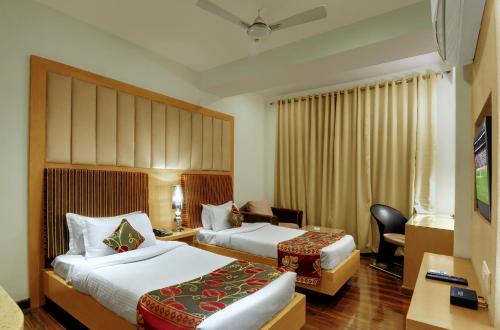 a hotel room with two beds and a desk at Hotel Balaji Central in Ratlām