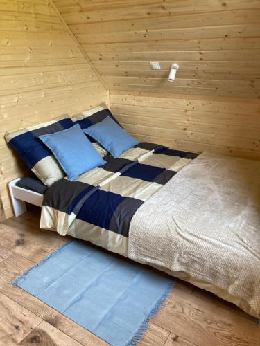 een bed in een houten kamer met blauwe kussens bij Domek nad rzeką in Wierzchlas