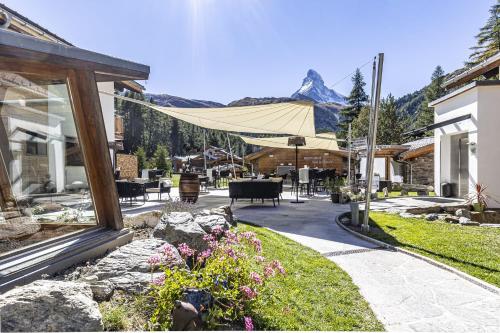 a house with a patio with mountains in the background at Hotel Hemizeus & Iremia Spa in Zermatt