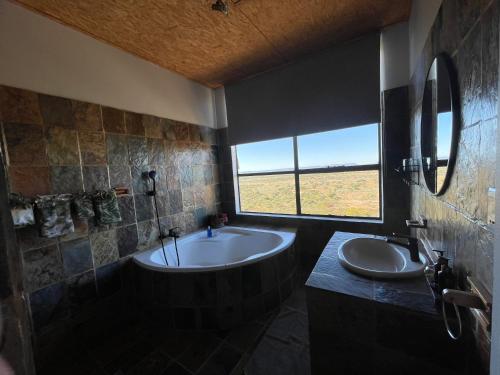 ein Bad mit einer Badewanne, 2 Waschbecken und einem Fenster in der Unterkunft Aloegrove Safari Lodge in Otjiwarongo