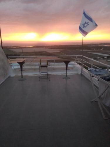 a flag on the top of a cruise ship with the sunset at דירה נעימה בקומה 11 בזכרון יעקב, מרפסת משקיפה לים in Zikhron Ya‘aqov