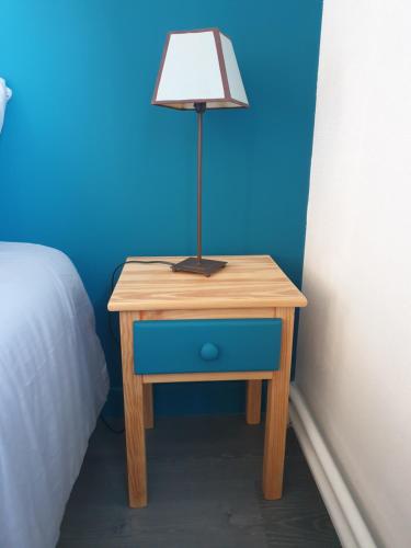 une table avec une lampe à côté d'un lit dans l'établissement Accueil familial & convivial - chambre privée chez l'habitant, à Agen