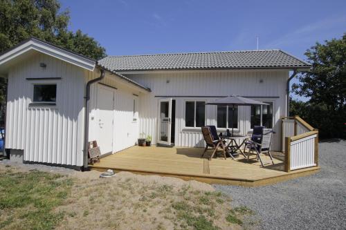 a house with a wooden deck with a table and chairs at Fräsch nybyggd stuga på Getterön Varberg in Varberg
