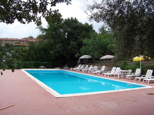 ein Pool mit weißen Stühlen und einem Haufen von Plätzen in der Unterkunft Holiday Home in Paciano with Swimming Pool Terrace Billiards in Paciano