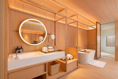 a bathroom with a sink and a mirror at The Taikang Sanya, a Tribute Portfolio Resort in Sanya