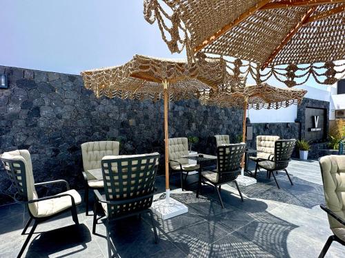grupa krzeseł i parasol na patio w obiekcie Venus Sunrise Suites & Villas w mieście Vourvoúlos