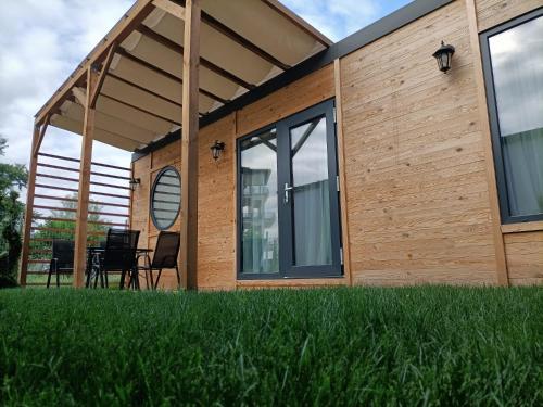 a wooden house with a large window and green grass at Tiny Village Mamaia Nord - House 1 in Mamaia Sat/Năvodari