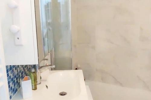 a white bathroom with a sink and a mirror at Studio meublé vue tour Eiffel proche paris JO 2024 in Saint-Maurice