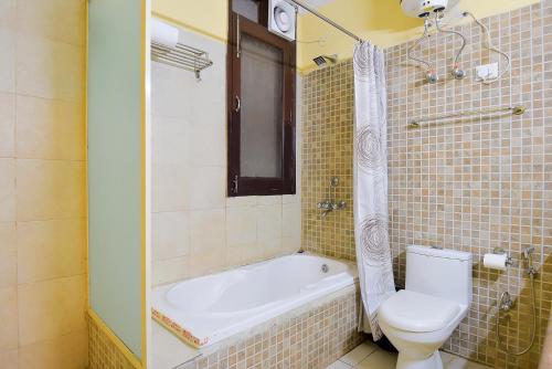 a bathroom with a toilet and a bath tub at BedChambers Serviced Apartments, Sushant Lok in Gurgaon