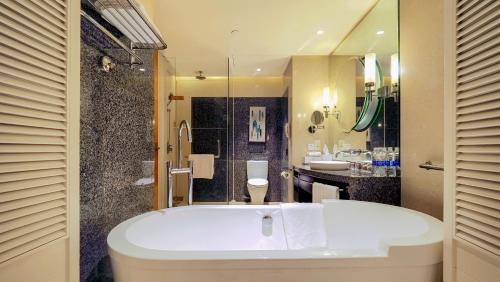 ein Bad mit einer Badewanne, einer Dusche und einem Waschbecken in der Unterkunft Sheraton Haikou Hotel in Haikou