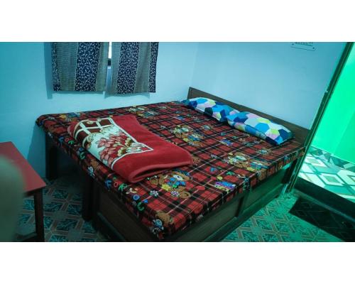 Una cama en una habitación con una manta. en Hotel Jagatguru, Barkot en Barkot