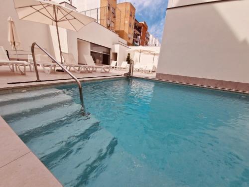 a large swimming pool with chairs and an umbrella at Virgen de los Reyes in Seville