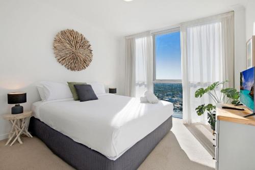 een witte slaapkamer met een groot bed en een groot raam bij Ocean Views Apartment in Southport Central in Gold Coast