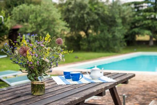 a wooden table with a vase of flowers on it at Villa Agriturismo Il Pratone in Castiglione dʼOrcia