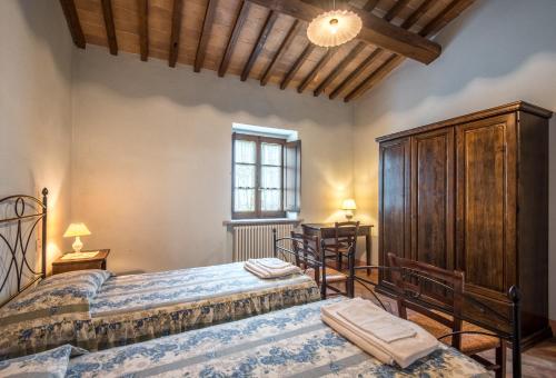 a bedroom with two beds and a wooden cabinet at Villa Agriturismo Il Pratone in Castiglione dʼOrcia