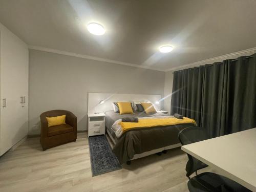 a bedroom with a bed and a chair at De Tuin Accommodation in Cape Town