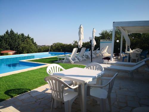 a patio with white tables and chairs next to a pool at B&B Villa Lena in Turi