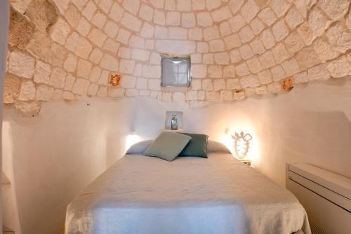 1 dormitorio con 1 cama con pared de piedra en Trullo Nostress with pool, en Ceglie Messapica