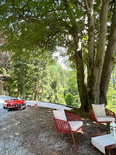 a red car parked next to a tree with chairs at Villa Pia Lena in Magreglio