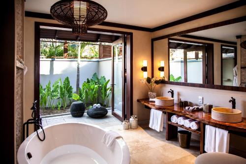 ein Badezimmer mit einer großen Badewanne und einem großen Fenster in der Unterkunft STORY Seychelles in Beau Vallon