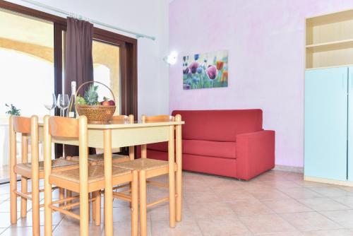a dining room with a table and a red couch at La Costa View in Arzachena