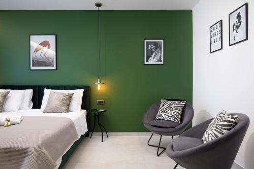 Habitación de hotel con paredes verdes y 2 sillas en Twins Amphitheatre Apartments, en Pula