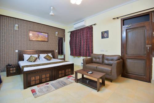 ein Schlafzimmer mit einem Bett, einem Sofa und einem Stuhl in der Unterkunft Studio Serviced Apartments near Fortis Hospital in Gurgaon