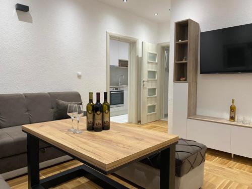 sala de estar con sofá y mesa con copas de vino en Apartmani Vasković, en Trebinje