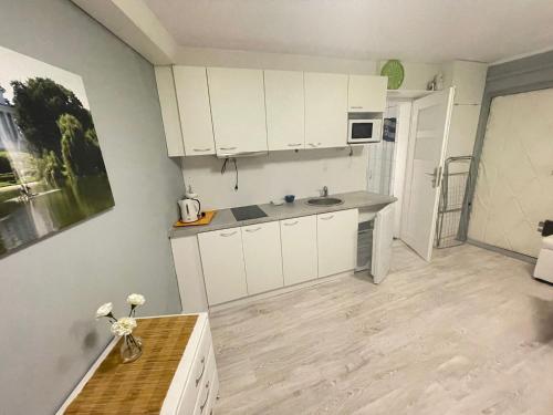 a kitchen with white cabinets and a wooden floor at Your Apart Saska Kępa in Warsaw