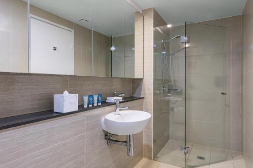 a bathroom with a sink and a shower at Meriton Suites Campbell Street, Sydney in Sydney