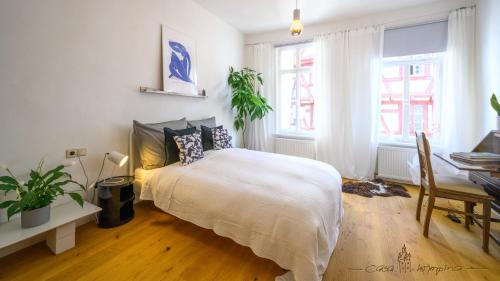 Schlafzimmer mit einem Bett, einem Schreibtisch und Fenstern in der Unterkunft Casa Wimpina - geschmackvolles Appartement im Herzen der Altstadt in Bad Wimpfen