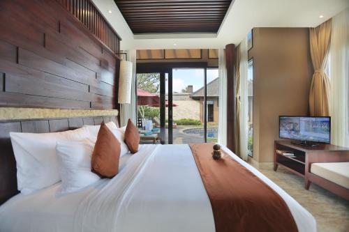 a bedroom with a large bed and a television at Ulu Segara Luxury Suites & Villas in Nusa Dua