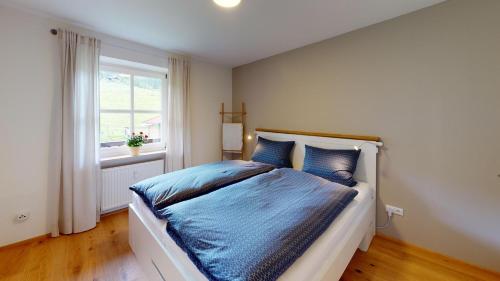 Un dormitorio con una cama con sábanas azules y una ventana. en Gipfelglück, en Bischofswiesen