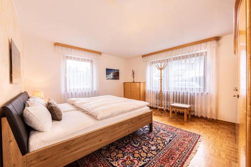 um quarto com uma cama grande e 2 janelas em Ferienwohnung Reserl in Bischofswiesen em Bischofswiesen