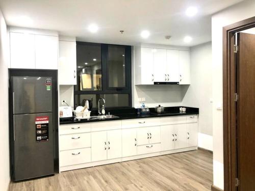 una cucina con mobili bianchi e un frigorifero nero di Rental Apartment - LEVUHOUSE a Nha Trang