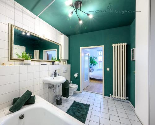 een badkamer met een wit bad en een groene muur bij Casa Wimpina - geschmackvolles Appartement im Herzen der Altstadt in Bad Wimpfen