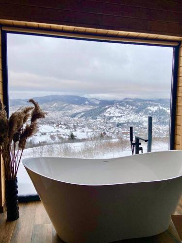 a bath tub in a room with a large window at Under Sky Slavske - Котеджі з Теплим басейном ,чаном-джакузі, панорамною ванною та PlayStation 5 in Slavske