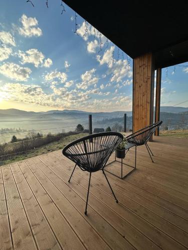 two benches sitting on a wooden deck with a view at Under Sky Slavske - Котеджі з Теплим басейном ,чаном-джакузі, панорамною ванною та PlayStation 5 in Slavske